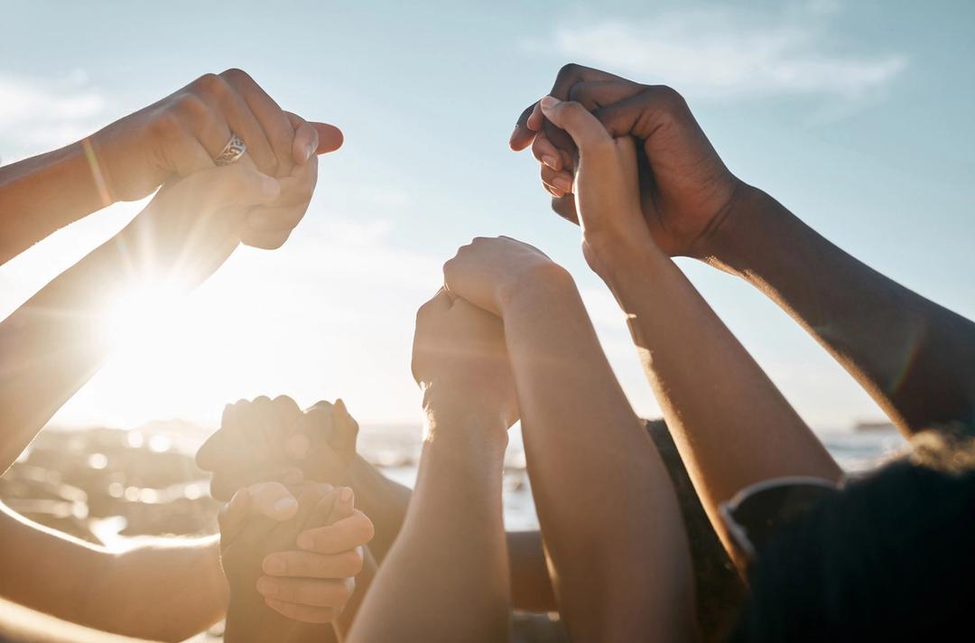 A group of people with their arms in the air holding hands.