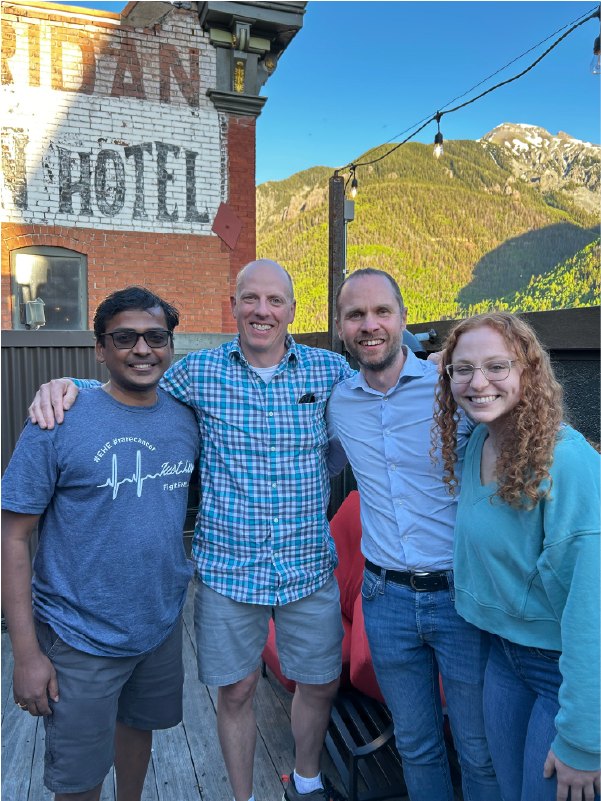 Four people stand closely for a photo