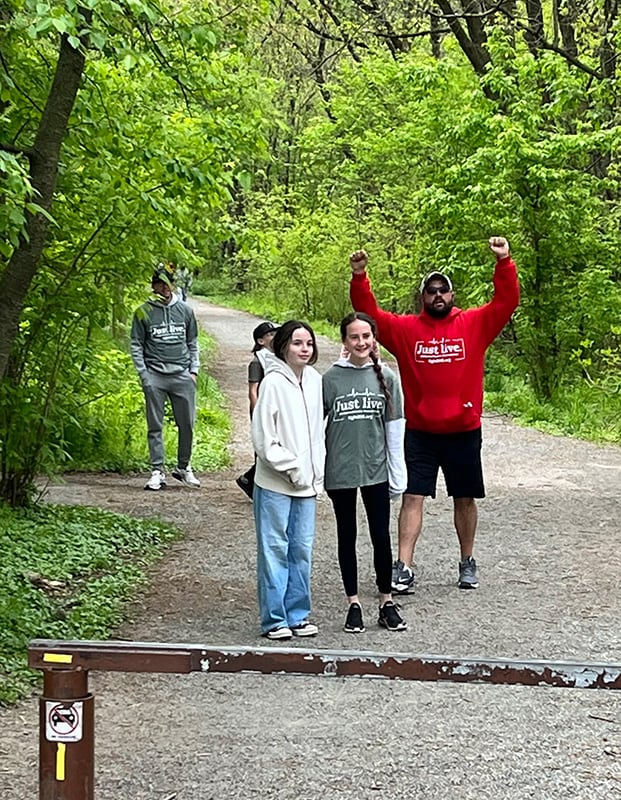 A group of people on the trail, one main raises his fists up in triumph