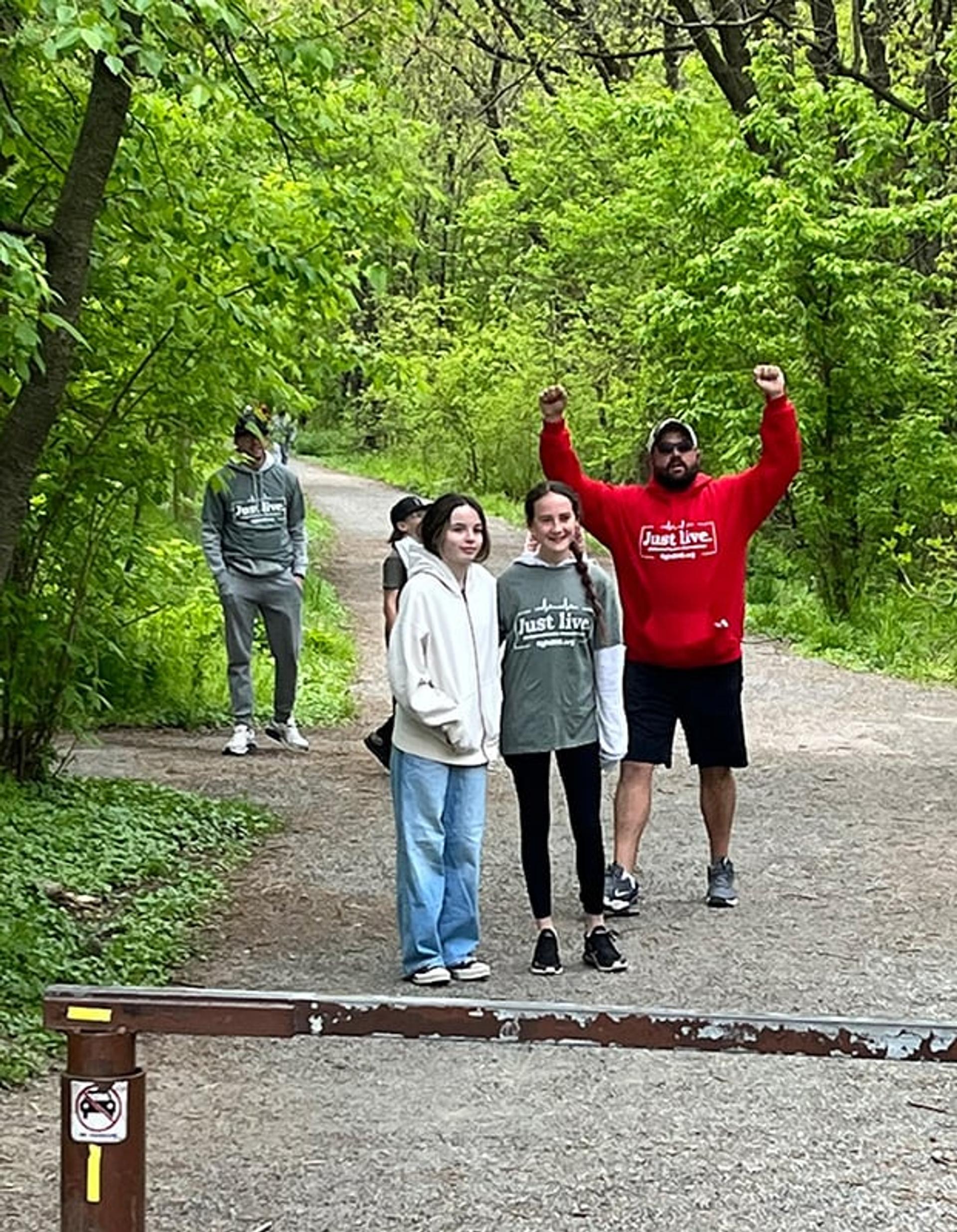 A group of people on the trail, one main raises his fists up in triumph