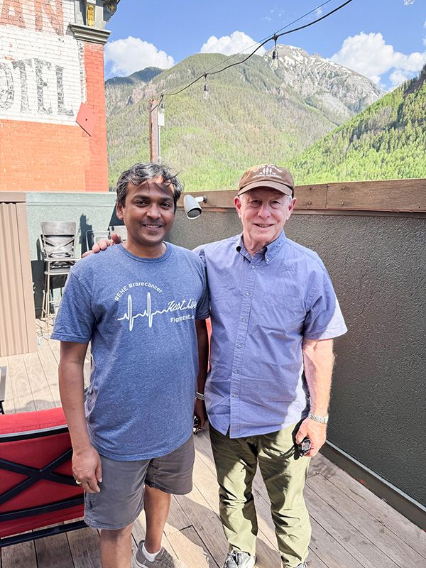 Two gentlemen take a photo together in front of a scenic mountain view