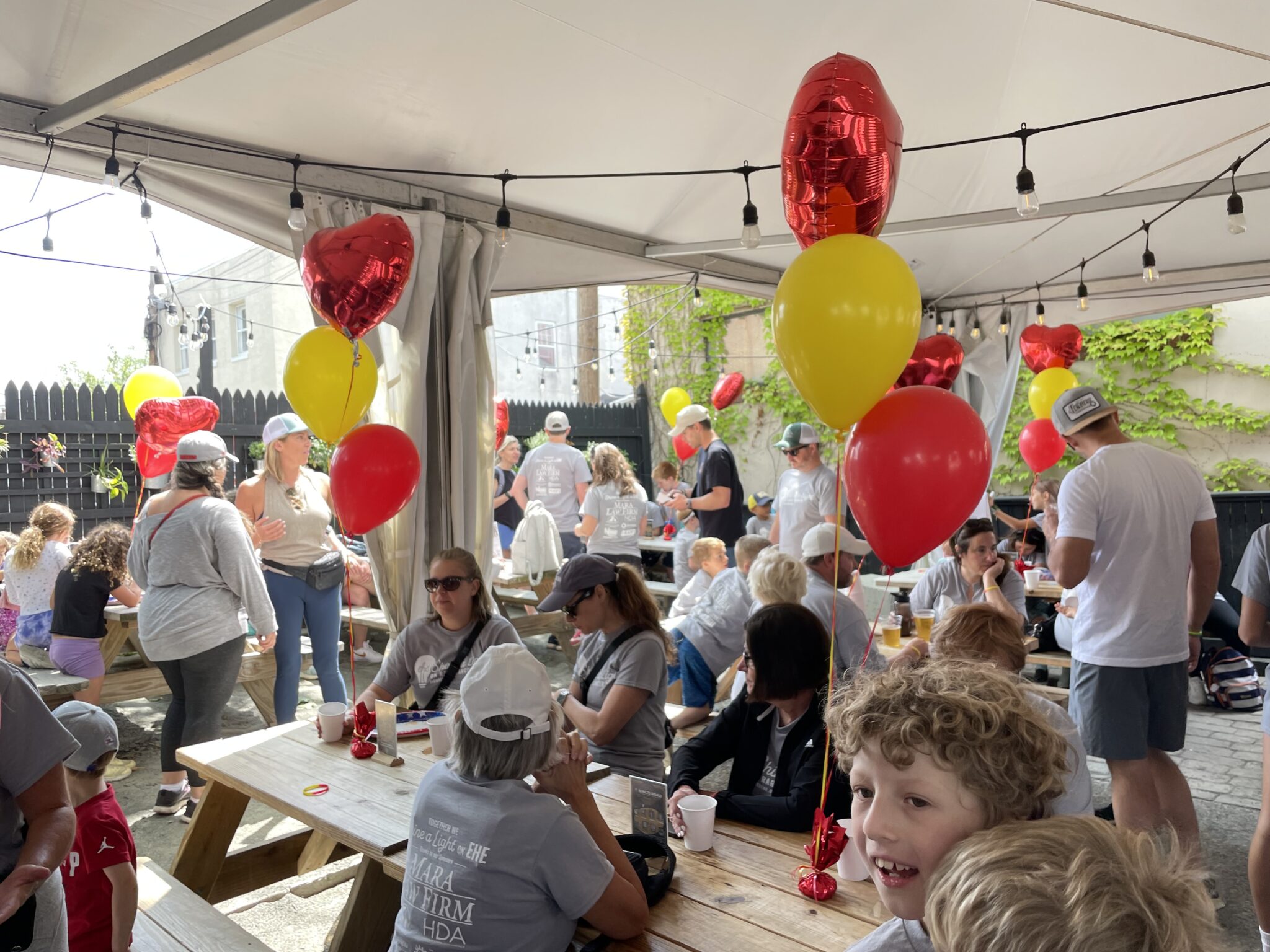 A large outdoor party showing off all the attendees with red and yellow balloons