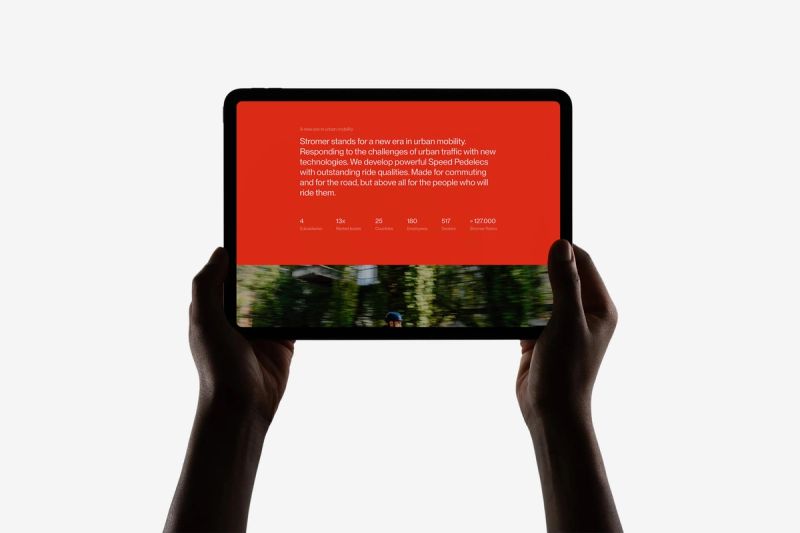 Silhouetted hands hold a tablet displaying a red screen with text about urban mobility and a blurred image.
