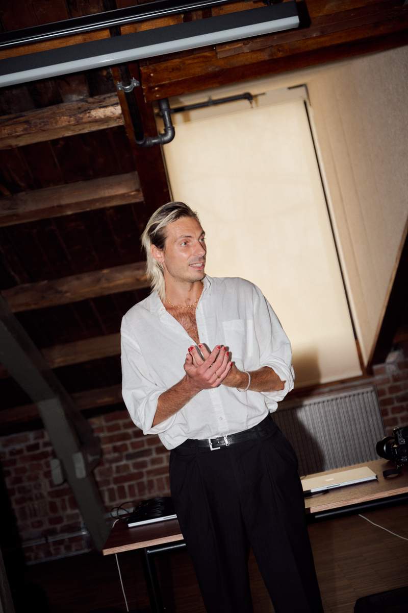 a man in a white shirt and black pants stands in a room