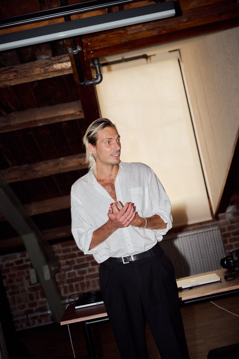 a man in a white shirt and black pants stands in a room