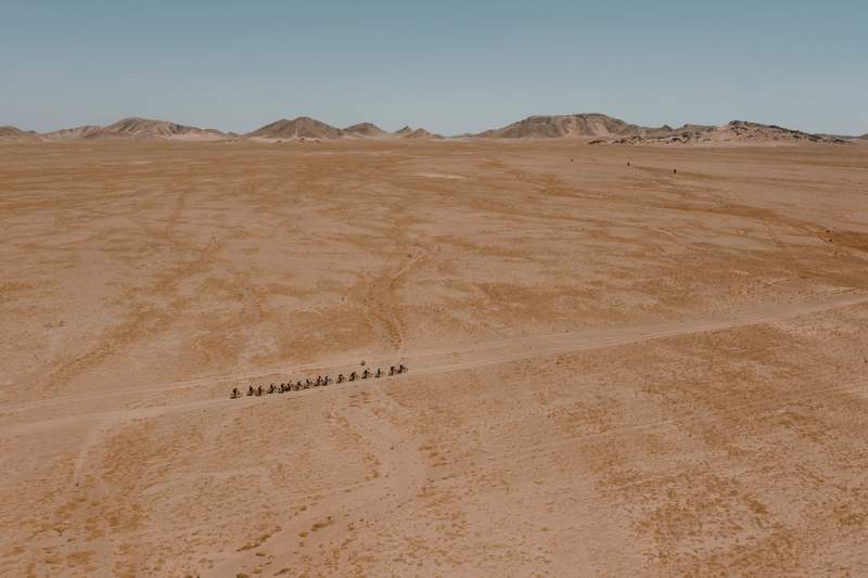 an aerial view of a group of people riding camels in the desert .