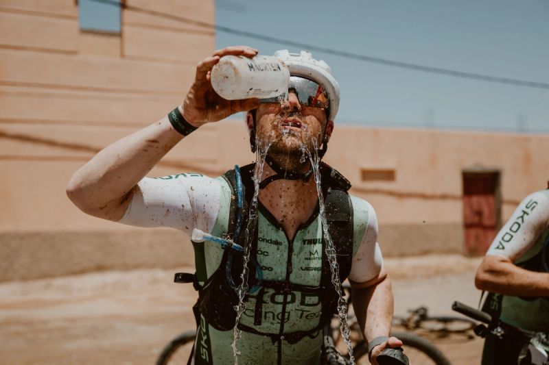 a man is drinking water from a bottle while riding a bike .
