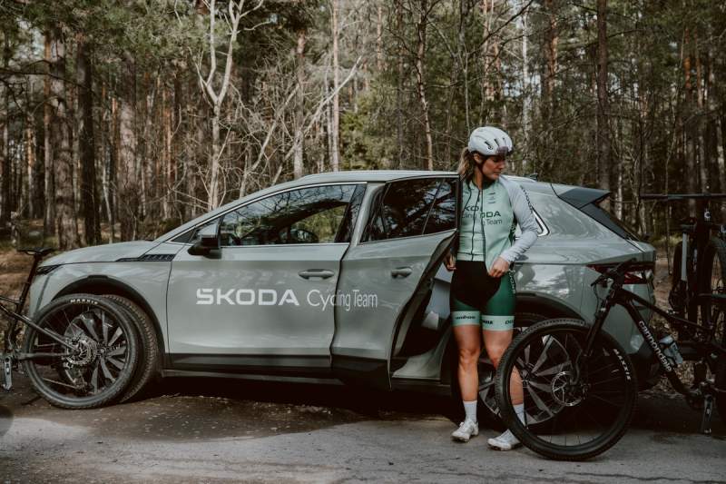 a woman is getting out of a skoda car with a bicycle .