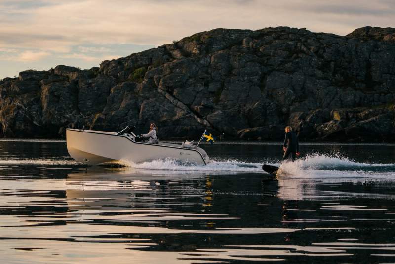 a man is waterskiing next to a boat in the ocean .