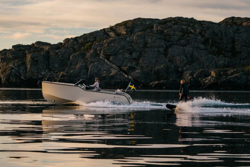 a man is waterskiing next to a boat in the ocean .