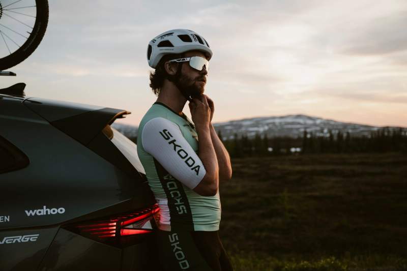 a man wearing a helmet and sunglasses is standing next to a car .