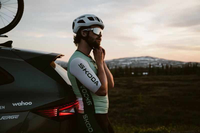 a man wearing a helmet and sunglasses is standing next to a car .