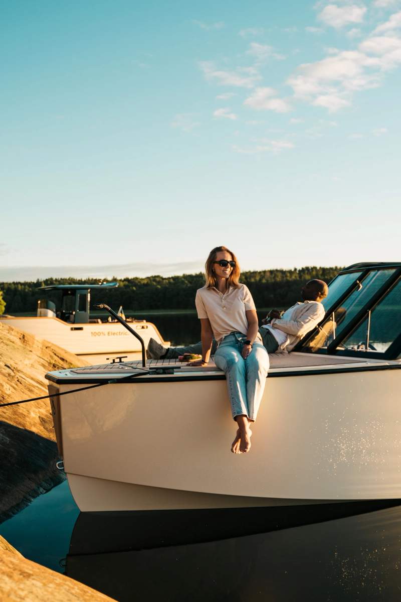 a woman sits on the side of a boat next to a man