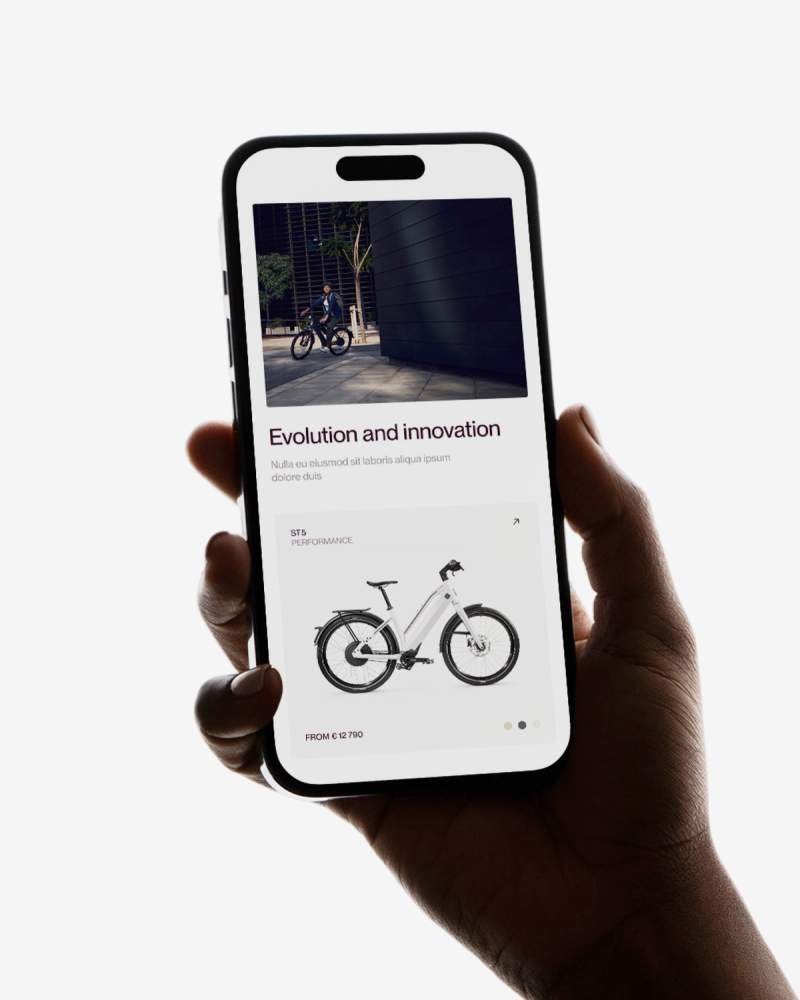 A hand holds a smartphone displaying a webpage with a white electric bicycle and the title "Evolution and innovation."