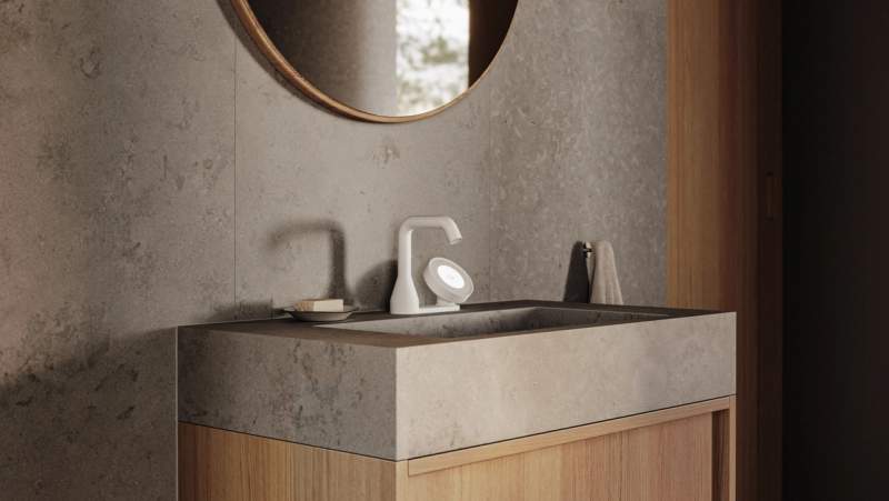 Modern bathroom vanity with a gray stone sink, white illuminated faucet, wooden cabinet, and round mirror.