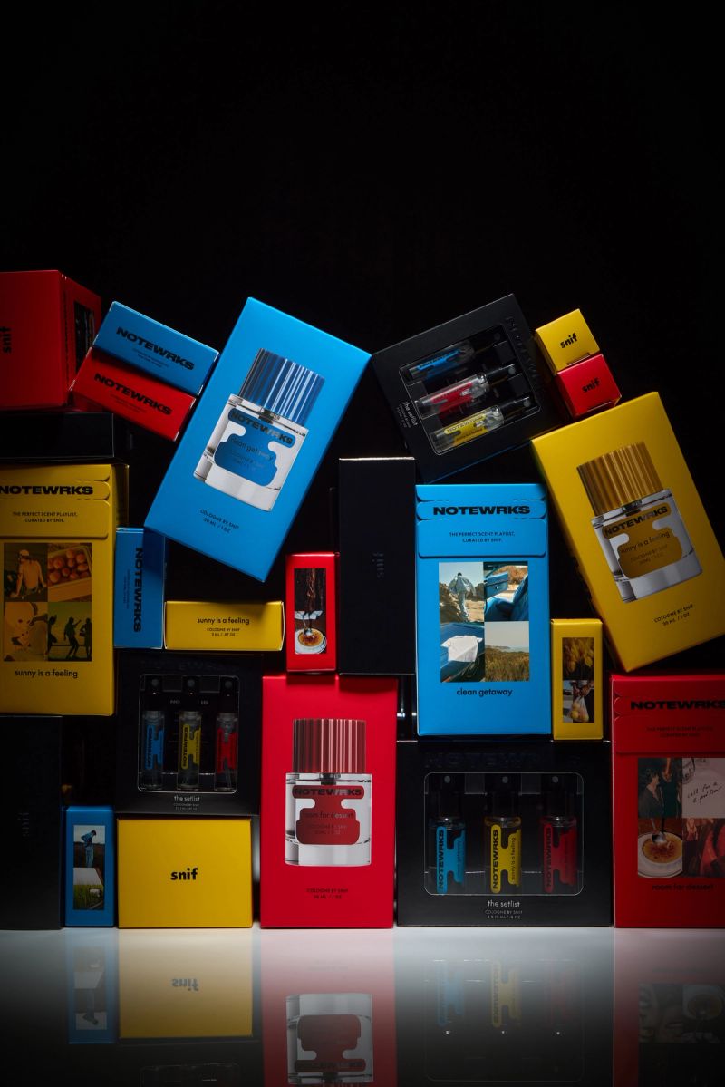A colorful collection of perfume bottles and boxes from brands "NOTEWRKS" and "snif" on a reflective surface.