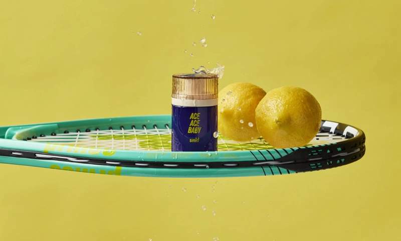 a tennis racket with a bottle of ace ace water and lemons on it .