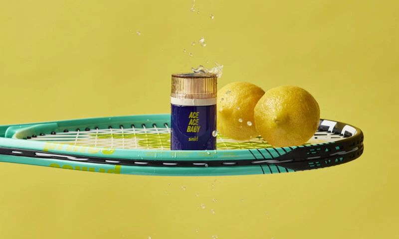 a tennis racket with a bottle of ace ace water and lemons on it .