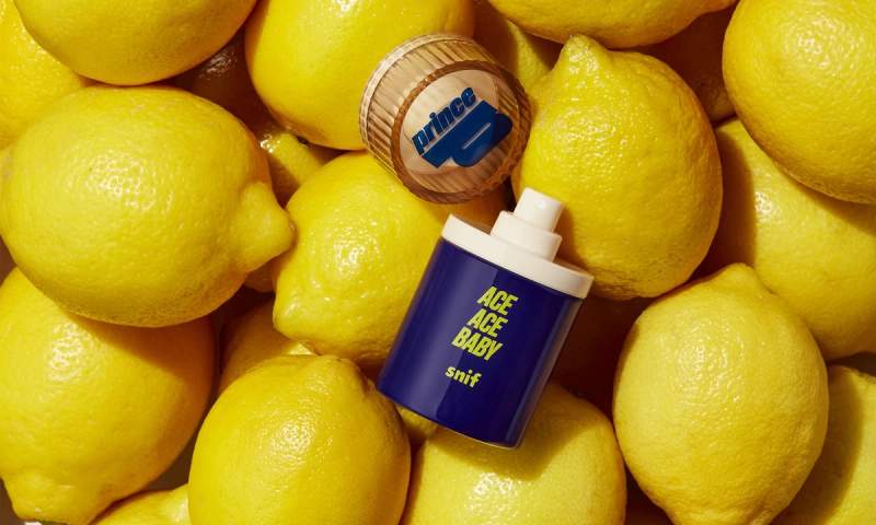 a bottle of ace ace baby perfume is sitting on top of a pile of lemons .