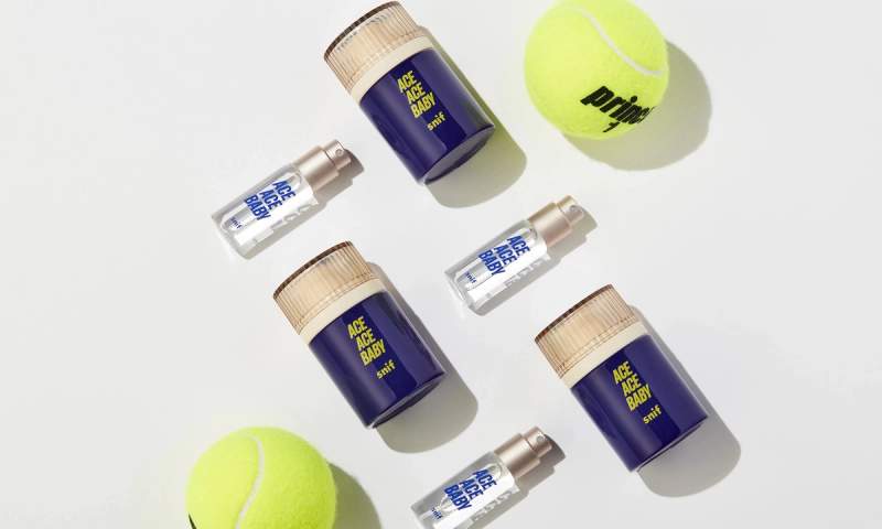 a tennis ball and bottles of ace ace baby cologne on a white surface .