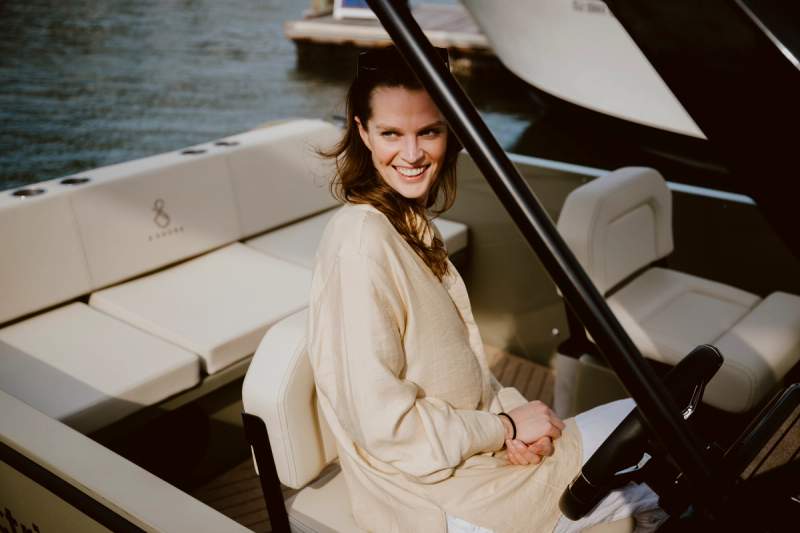 a woman is sitting in the driver 's seat of a boat .