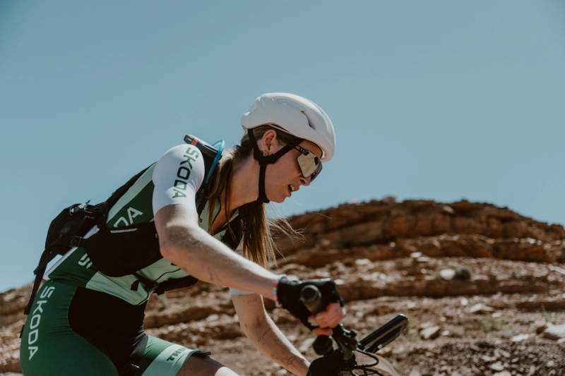 a woman is riding a bike on a dirt road .