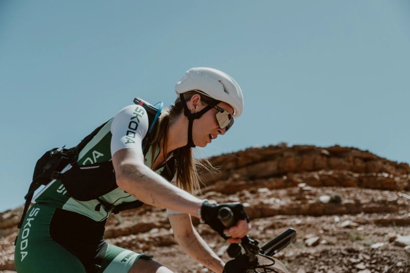 a woman is riding a bike on a dirt road .