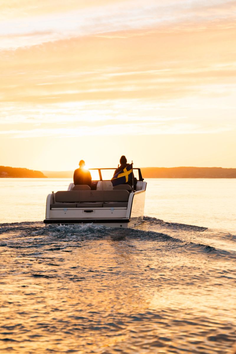 two people are riding a boat on a lake at sunset .