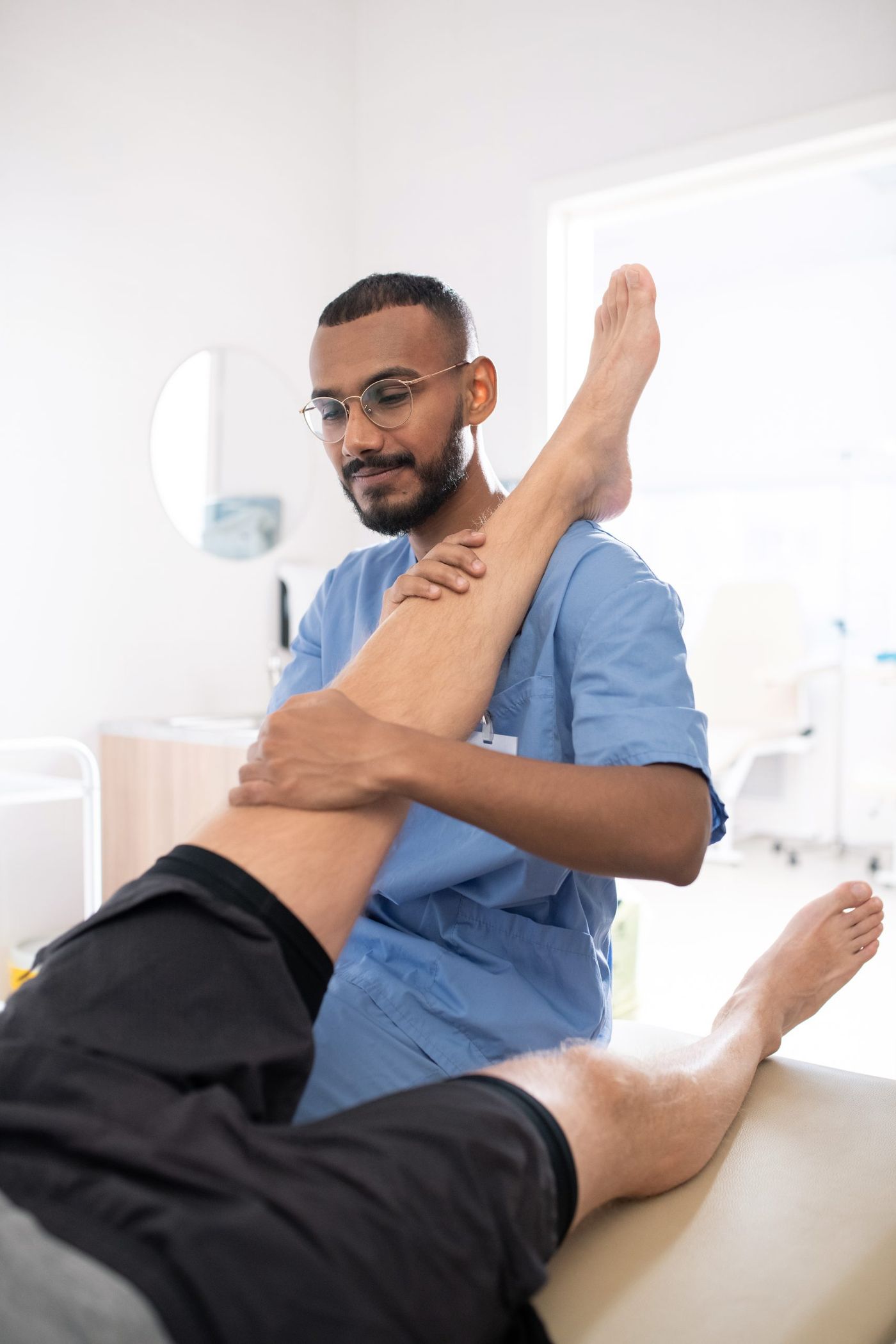 Physiotherapist assisting a patient with shoulder rehabilitation exercise under clinical supervision.