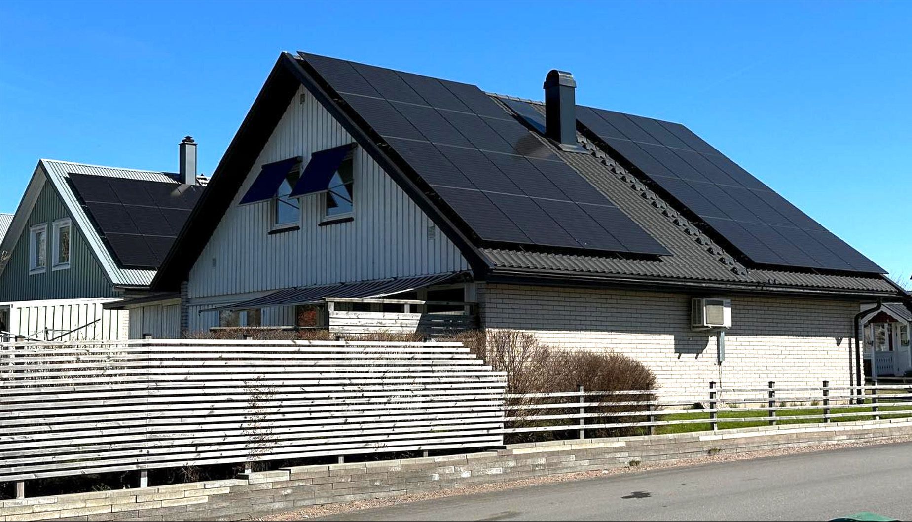 En villa med solpaneler mot en blå himmel.