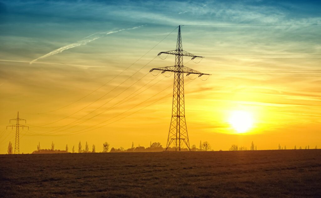 Power transmission tower silhouetted against a golden sunset