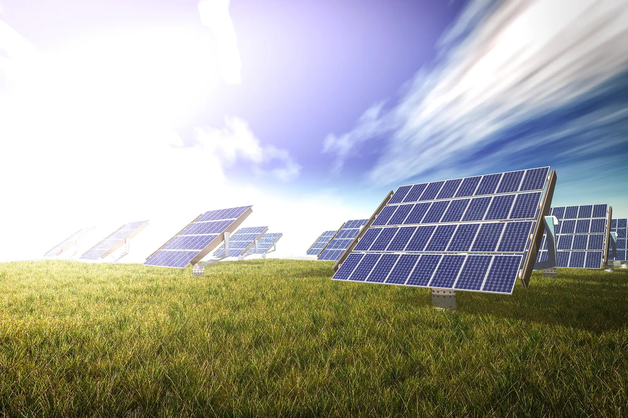 Ground-mounted solar panels on a grassy field under a bright sky