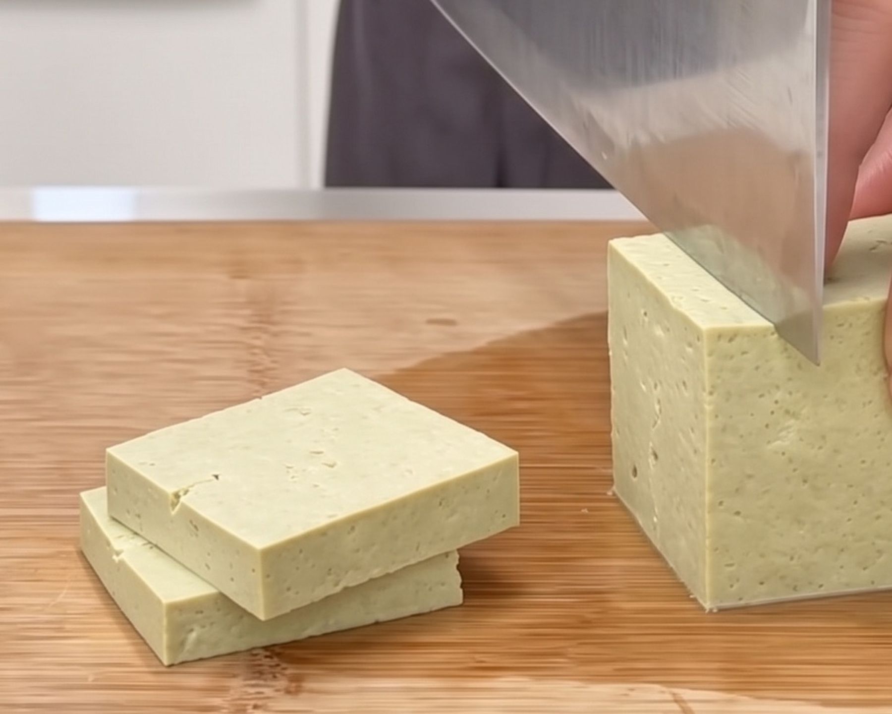 Slicing a block of firm tofu made from green soybeans