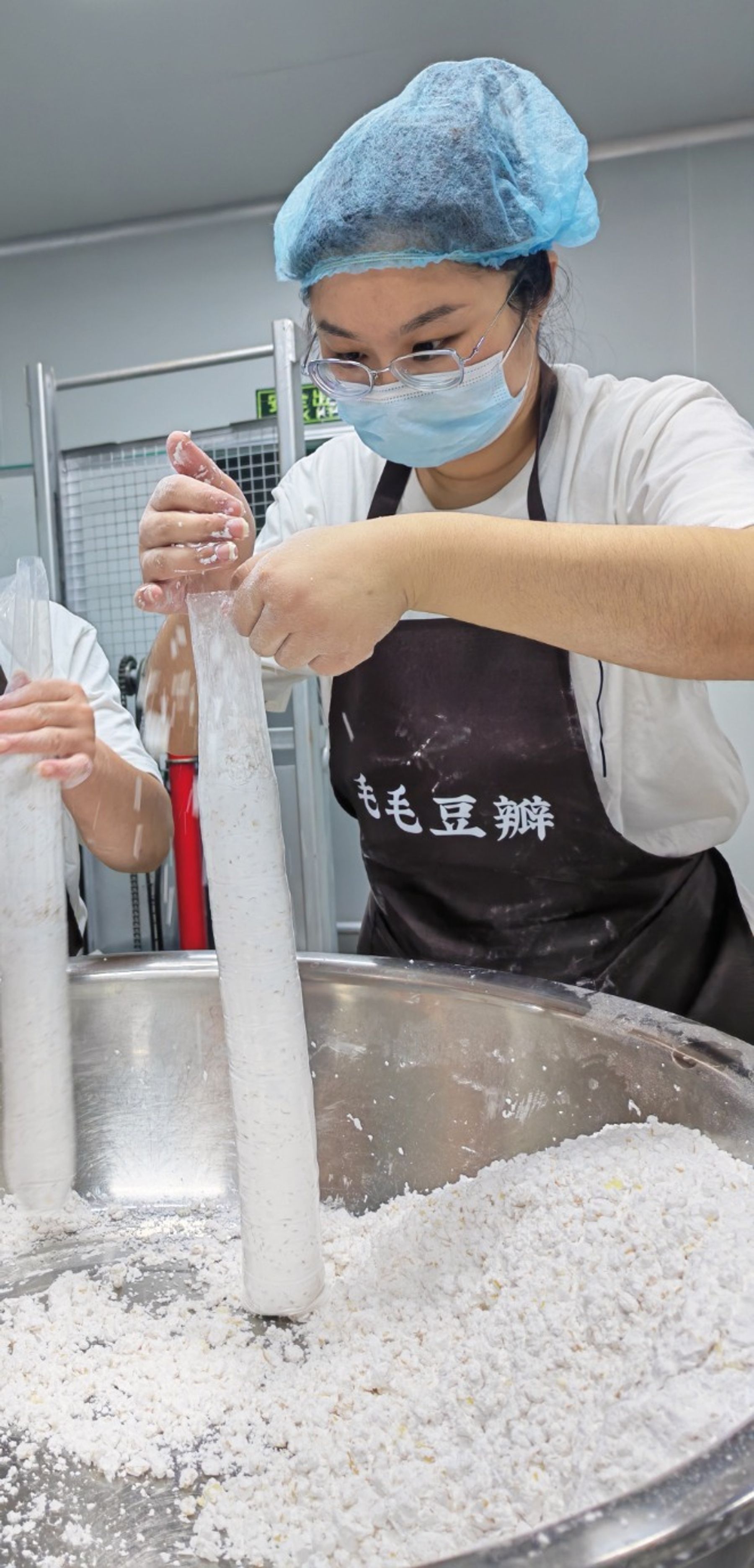 A worker mixing soybeans in a large steel bowl