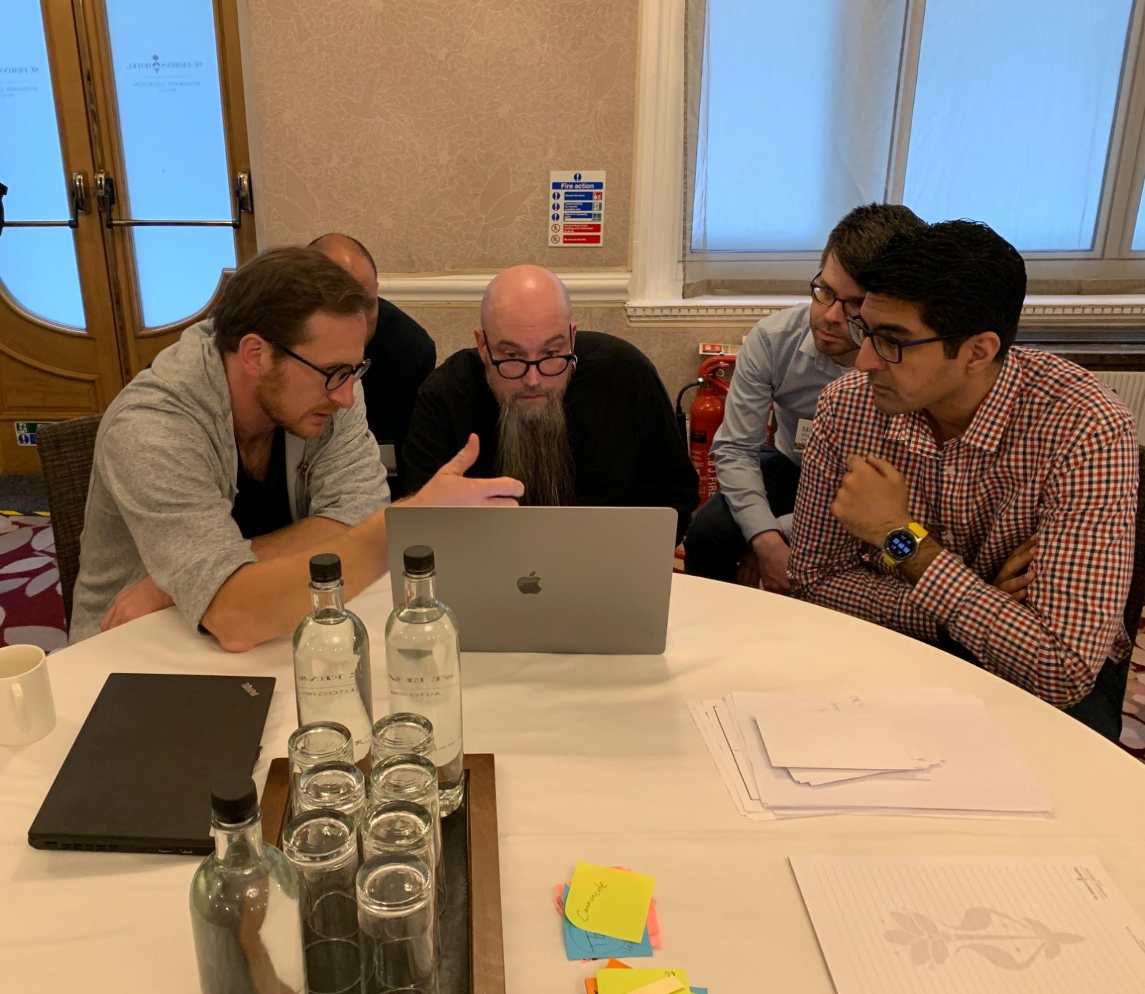 A group of people looking at a laptop.