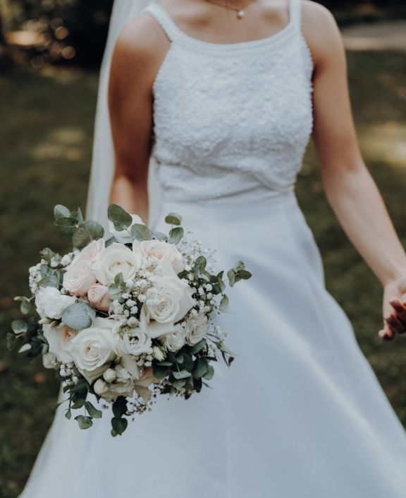 Klassische Hochzeitsfloristik mit weißen Rosen und Schleierkraut für eine festliche Tischdekoration