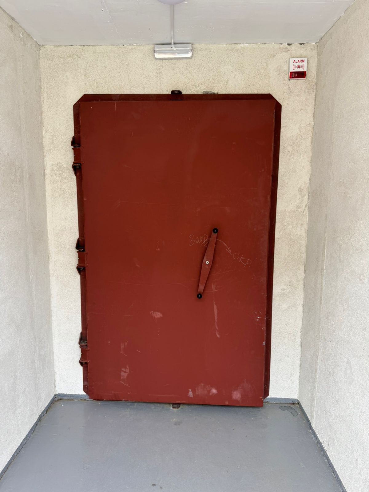 Rot lackierte Schutzraumtür in einem bestehenden Kellergang