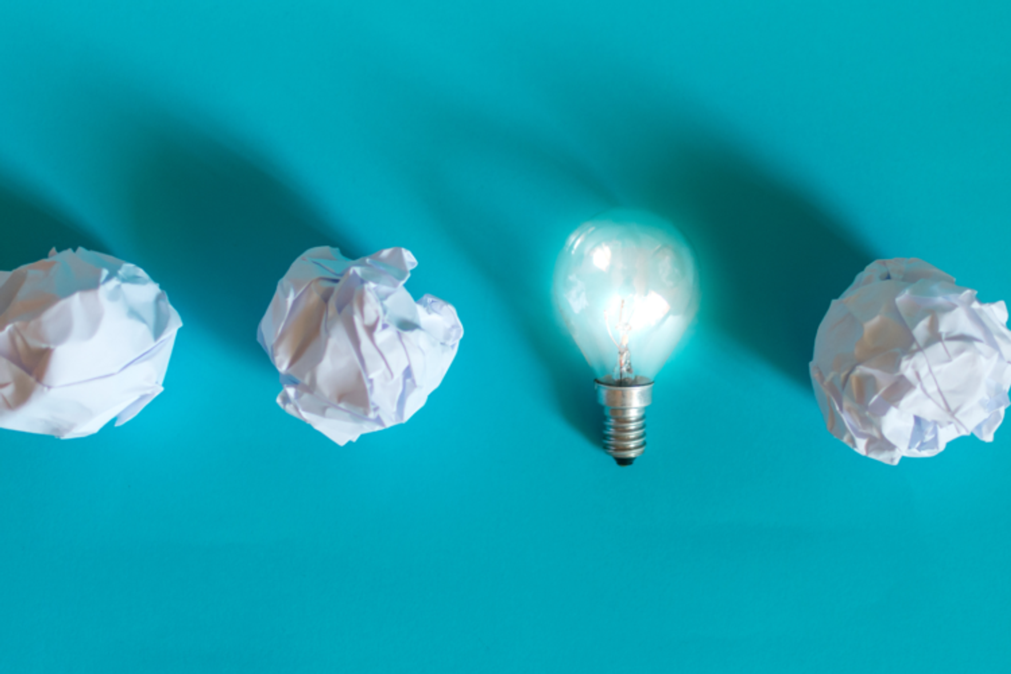 Three balls of screwed up paper in a row and one lightbulb.