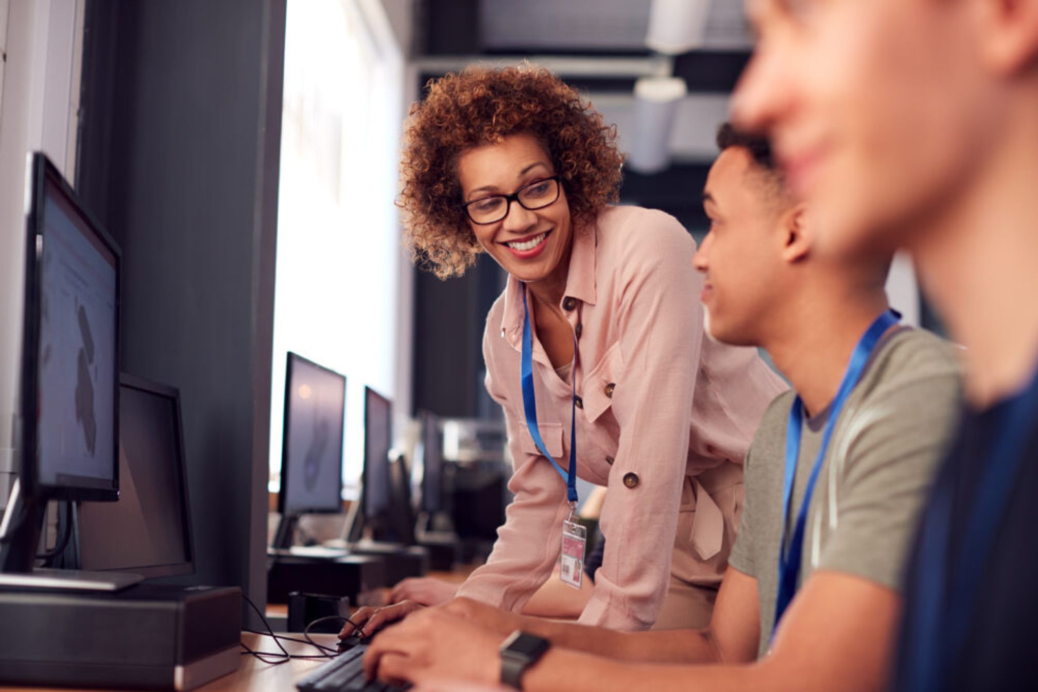 Teacher with older college students working in a computer lab.