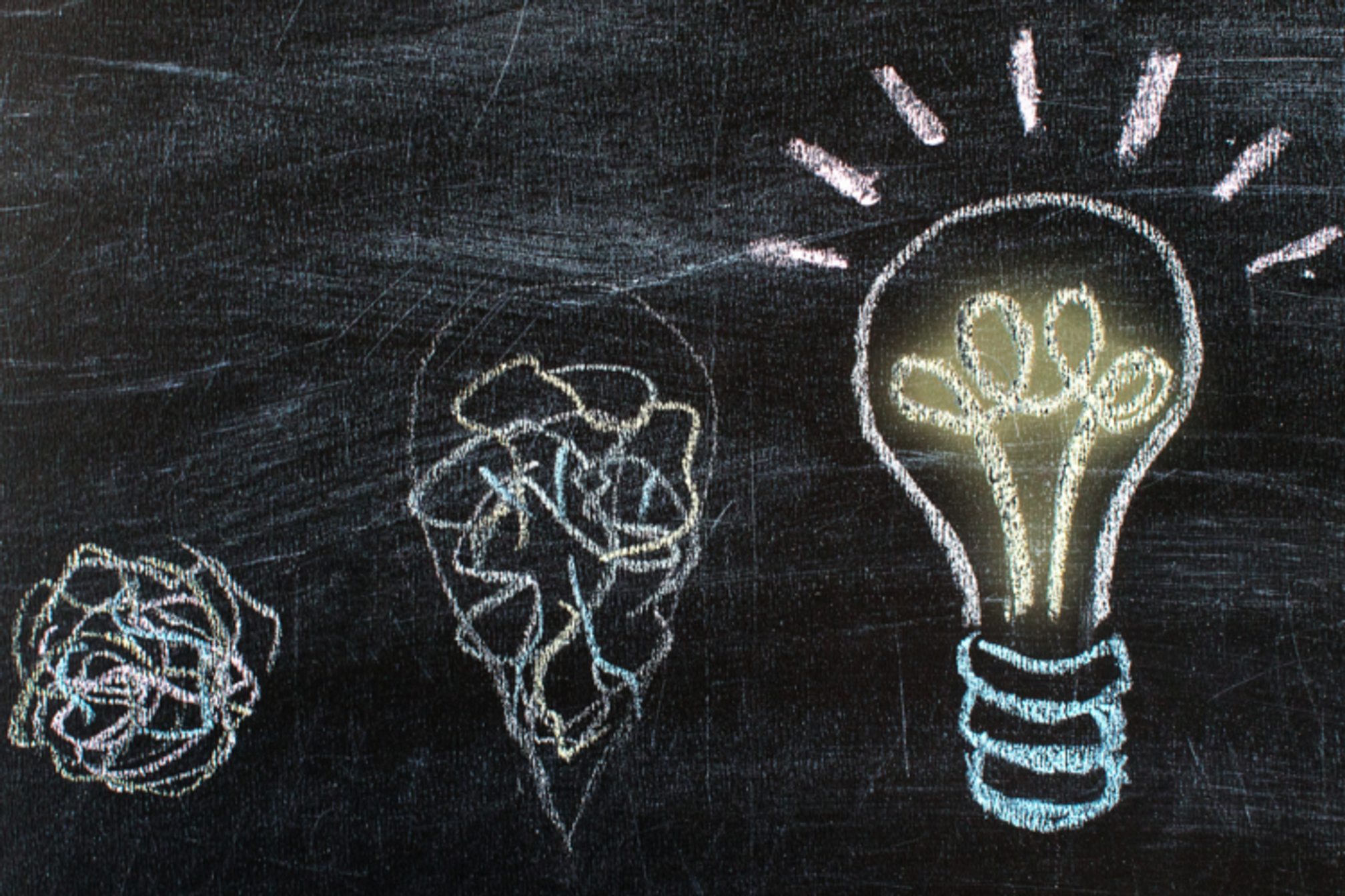 Chalkboard with scribbles gradually forming the image of a lightbulb.