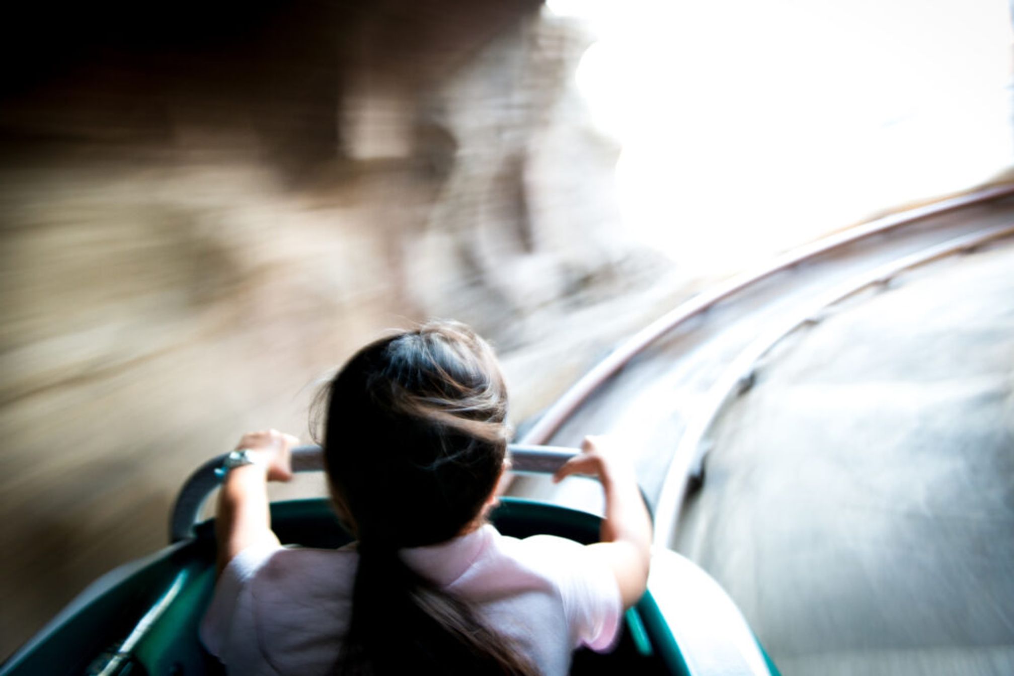 A girl going downhill on a rollercoaster, a view from behind.