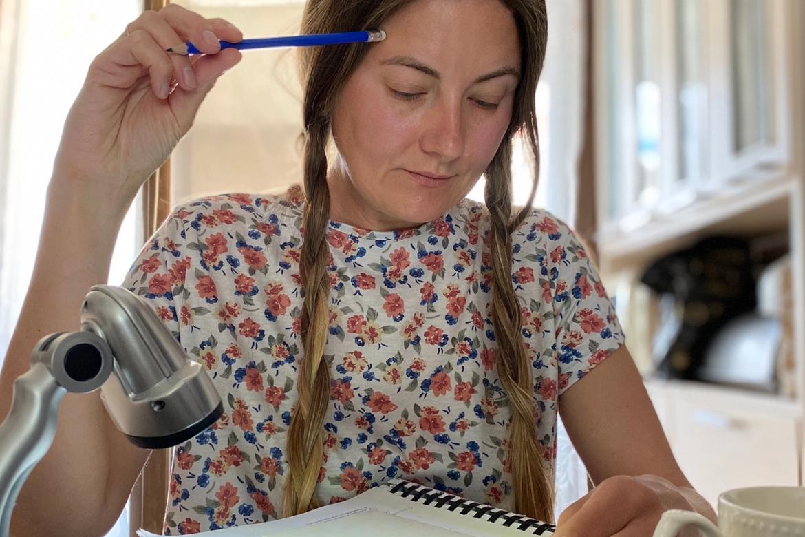A woman is sitting at a kitchen desk writing
