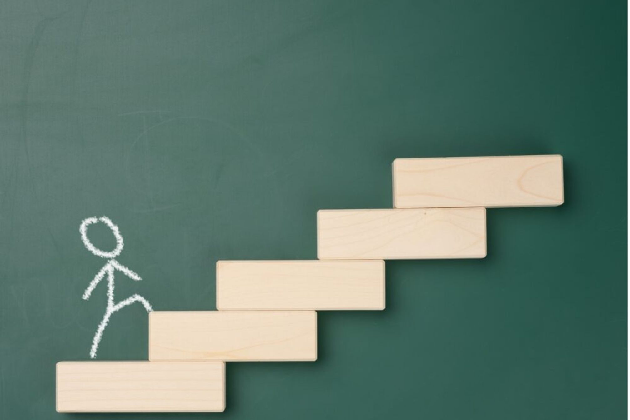 A stick man walking up some wooden blocks arranged as steps.