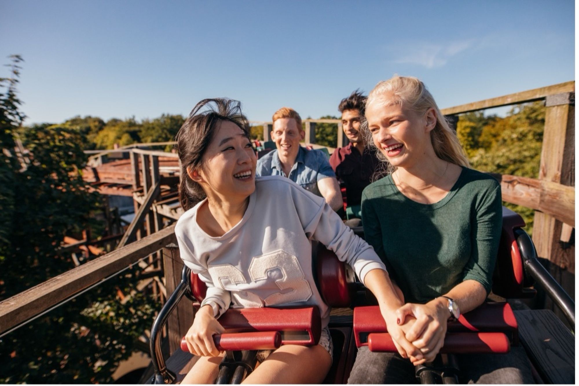 Young women holding hands on a rollercoaster