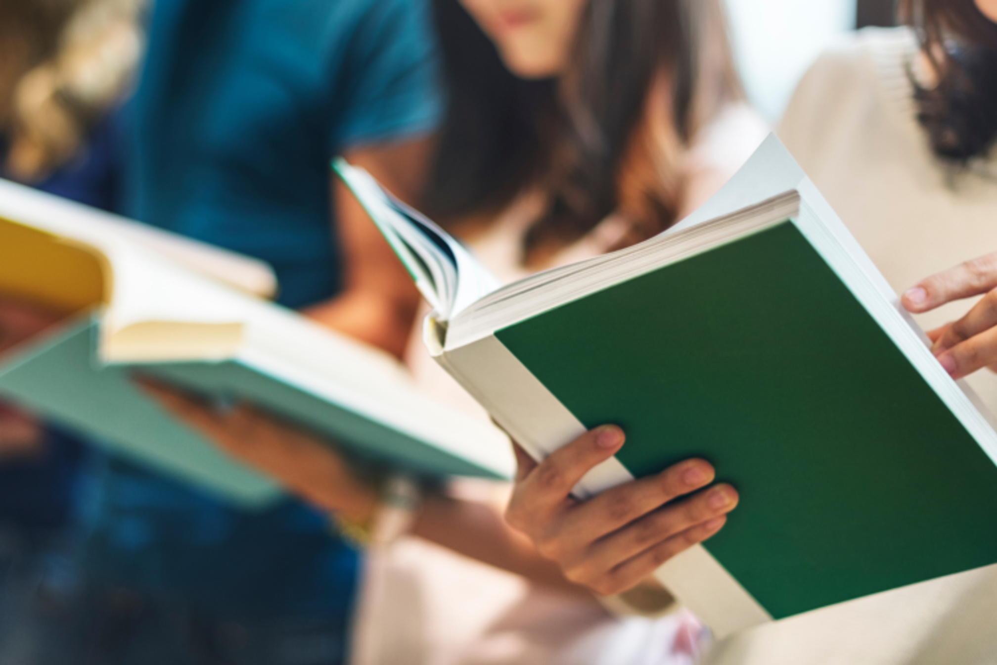 A row of people standing reading books.