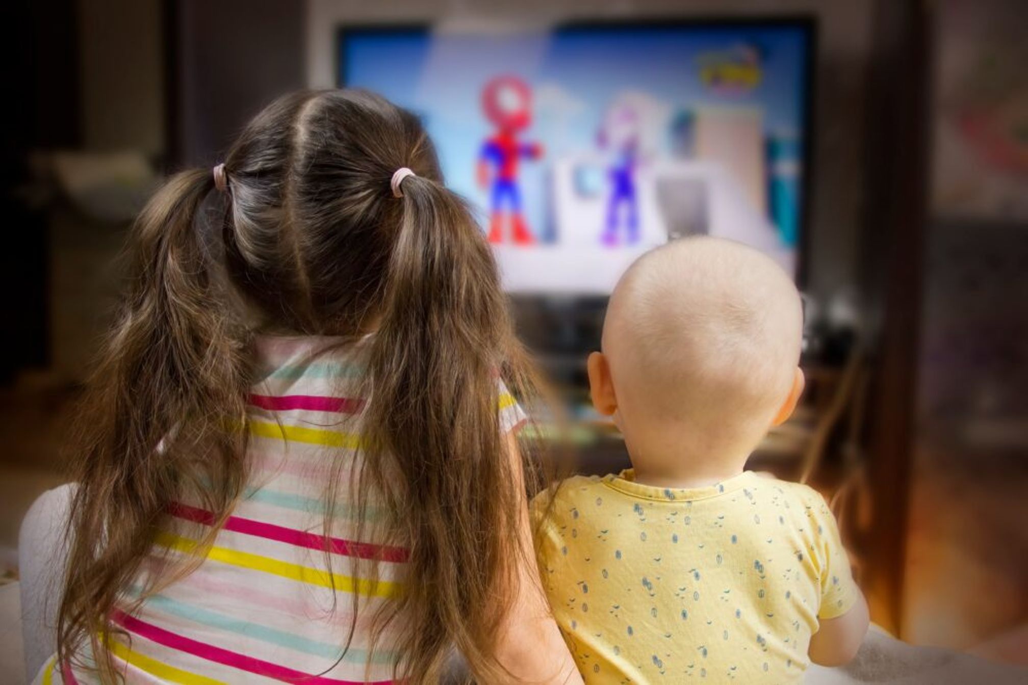 Two young children watching a children's TV programme.