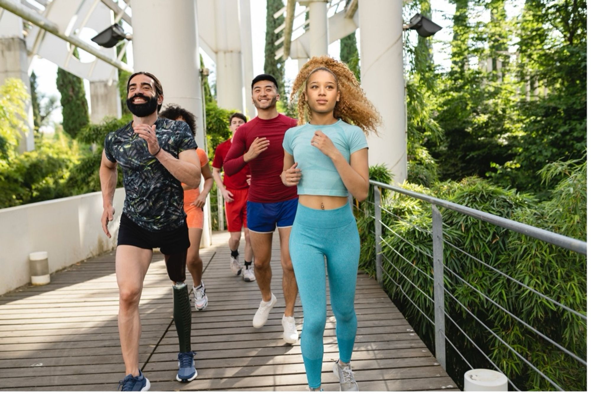 Young people running outdoors, one man has a prosthetic leg.