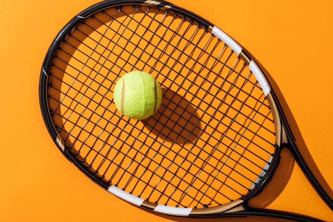 A tennis racket and ball on an orange background