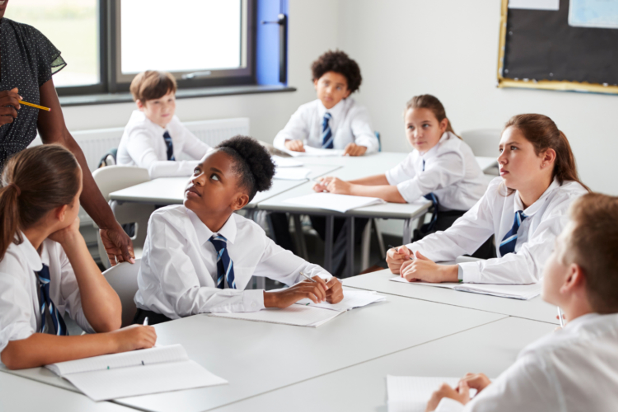 Secondary school students in a classroom listening to their teacher