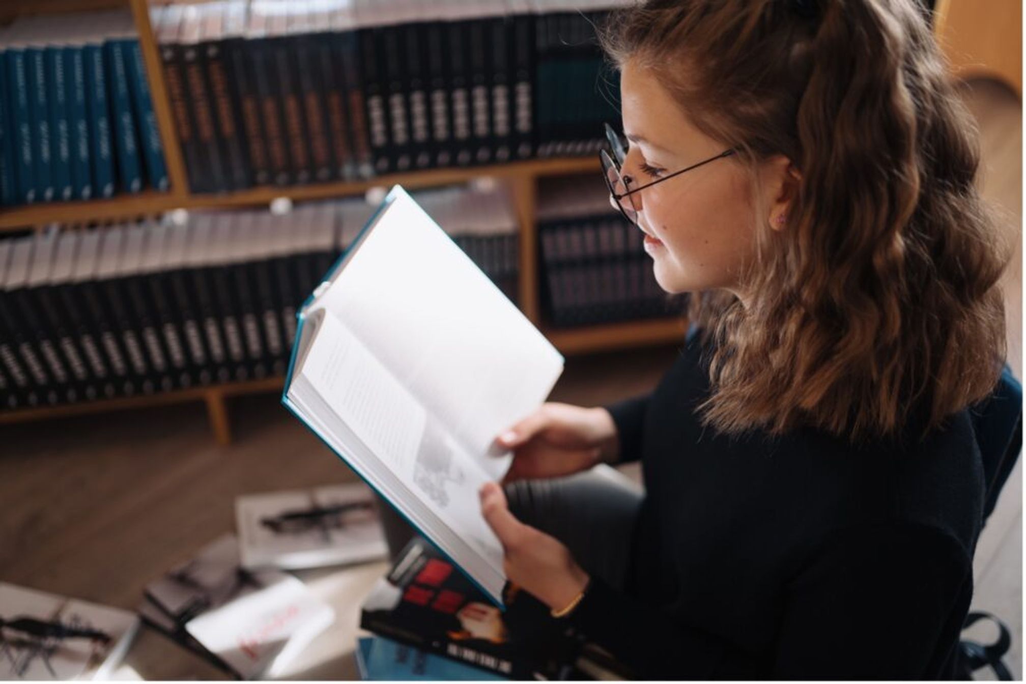 A young woman reading a book in a library.